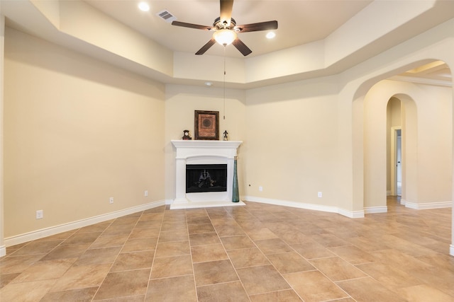 unfurnished living room with a tray ceiling and ceiling fan