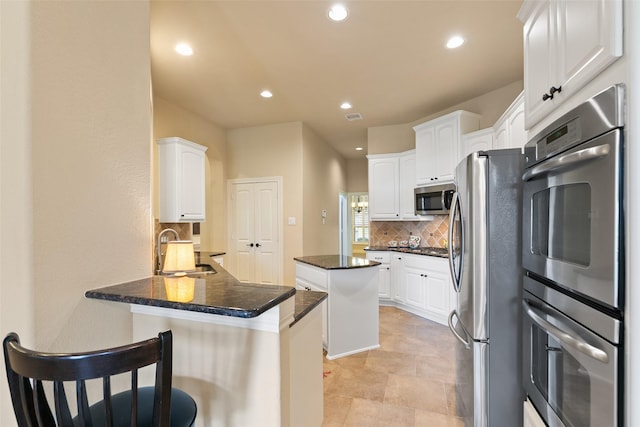 kitchen with a kitchen island, white cabinetry, sink, and appliances with stainless steel finishes