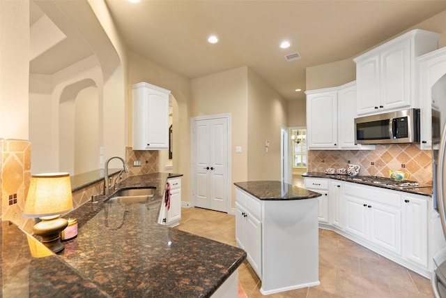 kitchen with sink, stainless steel appliances, tasteful backsplash, dark stone countertops, and white cabinets