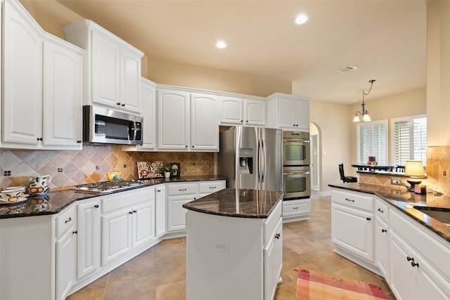 kitchen featuring decorative backsplash, stainless steel appliances, pendant lighting, white cabinets, and a center island