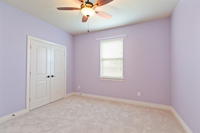 unfurnished bedroom featuring ceiling fan, light colored carpet, and a closet