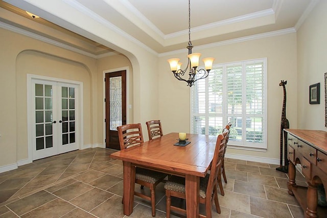 dining space with french doors, a tray ceiling, crown molding, and a notable chandelier