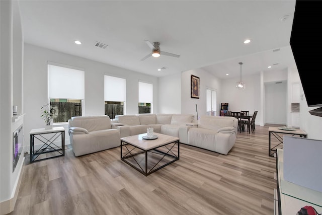 living room featuring light wood-type flooring, plenty of natural light, and ceiling fan