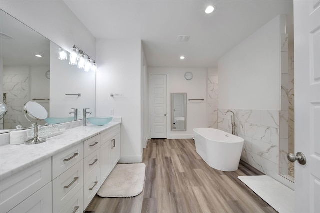 bathroom with hardwood / wood-style flooring, a washtub, tile walls, and vanity