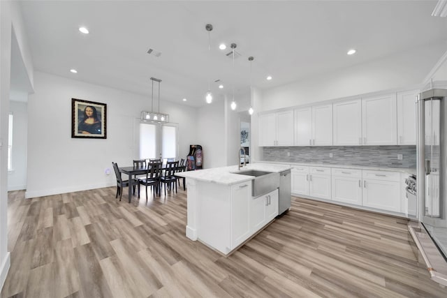 kitchen with white cabinetry, a center island with sink, light hardwood / wood-style flooring, and sink