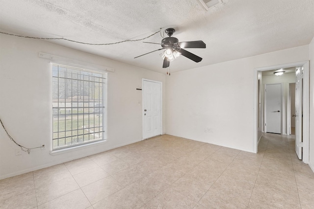 tiled spare room with a textured ceiling and ceiling fan