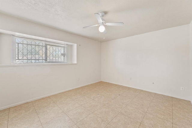 empty room featuring light tile patterned floors, a textured ceiling, and ceiling fan