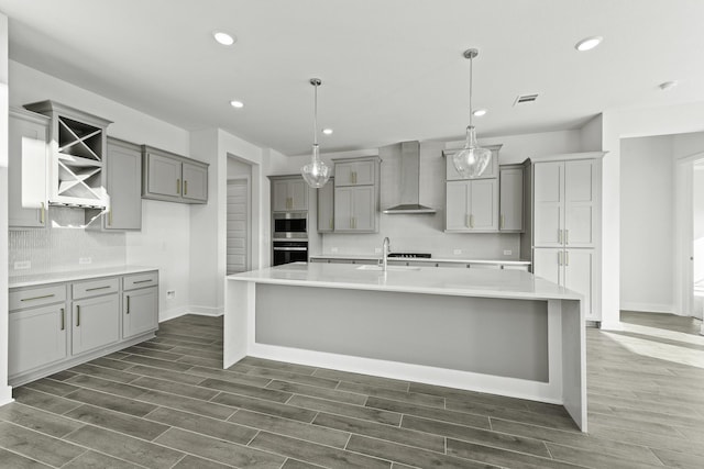 kitchen with gray cabinetry, pendant lighting, wall chimney range hood, and dark wood-type flooring