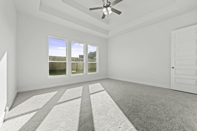 carpeted spare room featuring ceiling fan and a raised ceiling