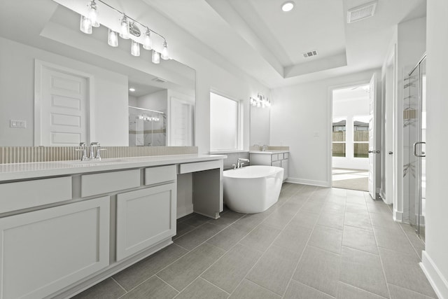 bathroom featuring vanity, tile patterned floors, separate shower and tub, and a raised ceiling