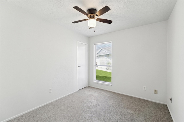 empty room with ceiling fan, carpet floors, and a textured ceiling