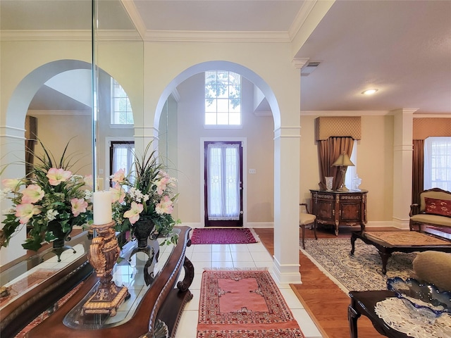 entrance foyer featuring light wood-type flooring, ornamental molding, and decorative columns