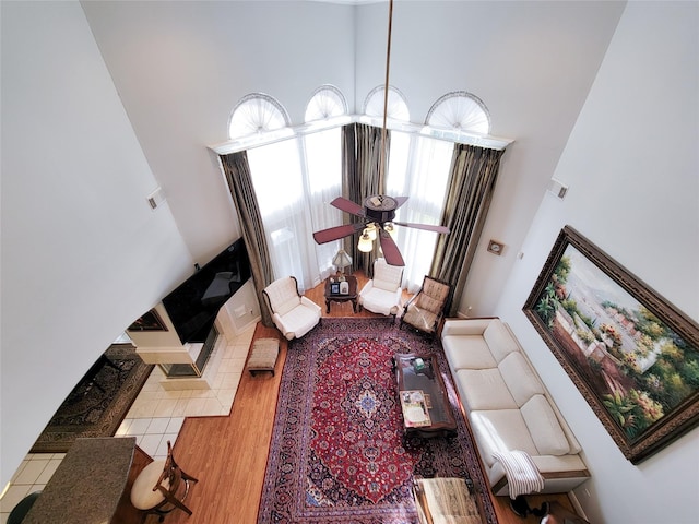 living room featuring ceiling fan, wood-type flooring, and a high ceiling