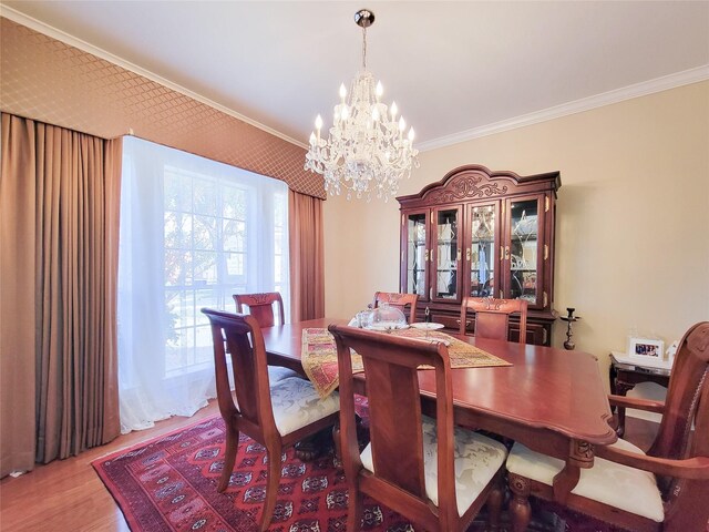 dining space with hardwood / wood-style floors, ornamental molding, and an inviting chandelier