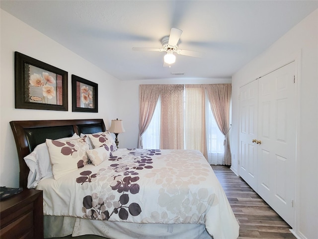 bedroom with a closet, dark hardwood / wood-style floors, and ceiling fan