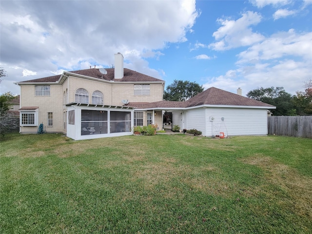 rear view of house with a lawn and a sunroom