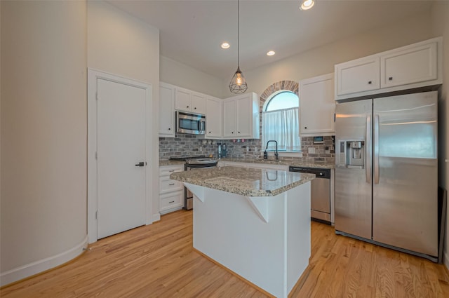 kitchen featuring stainless steel appliances, decorative light fixtures, a center island, light hardwood / wood-style floors, and white cabinetry