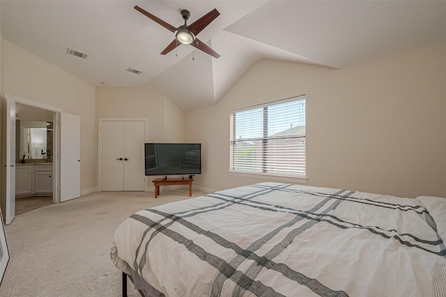 bedroom featuring ceiling fan, light colored carpet, lofted ceiling, and ensuite bath