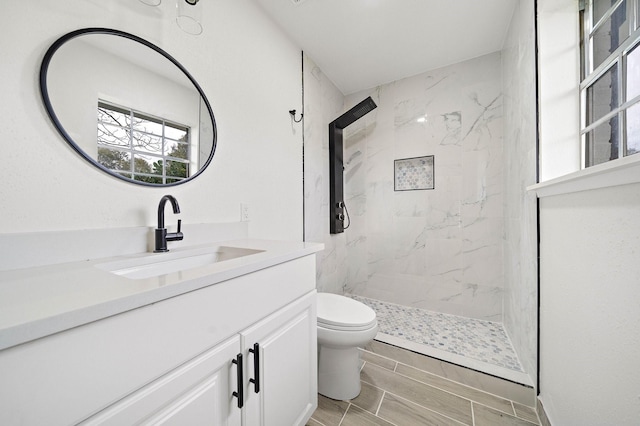 bathroom featuring vanity, toilet, and tiled shower