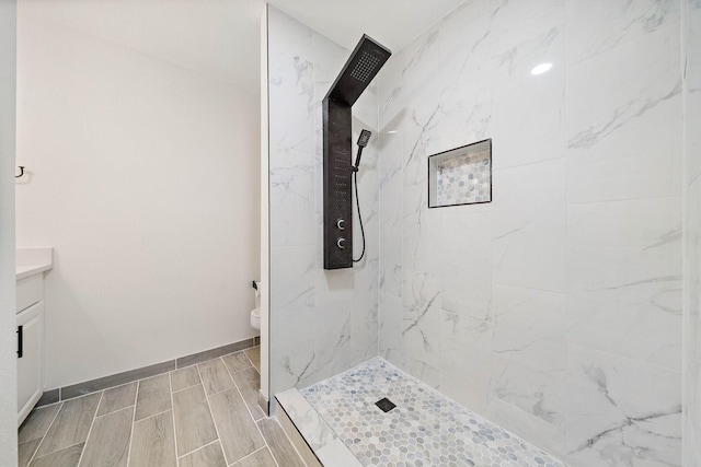 bathroom featuring vanity, toilet, and tiled shower