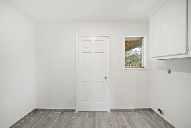 washroom with electric dryer hookup, hardwood / wood-style floors, and cabinets