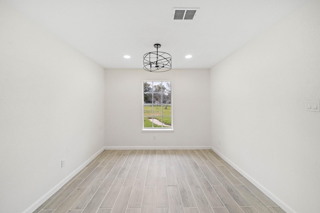 spare room with a chandelier and light hardwood / wood-style flooring