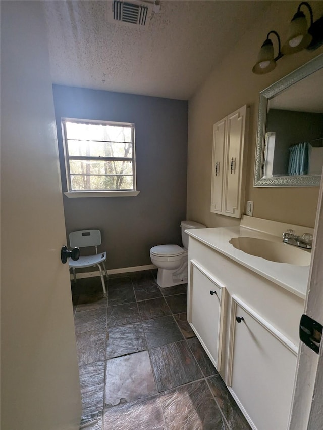 bathroom with vanity, toilet, and a textured ceiling