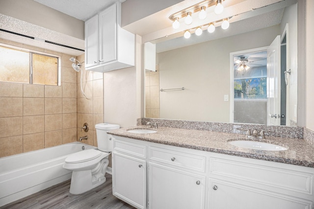 full bathroom with vanity, ceiling fan, wood-type flooring, toilet, and tiled shower / bath