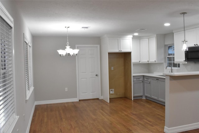 kitchen featuring dark hardwood / wood-style flooring, decorative light fixtures, and white cabinetry