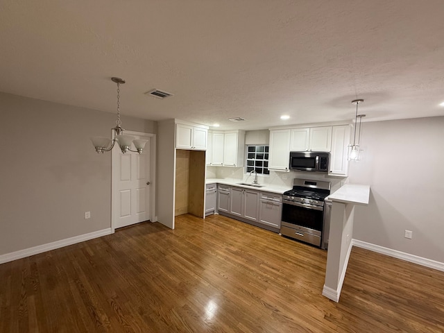 kitchen with pendant lighting, stainless steel range oven, white cabinetry, and sink