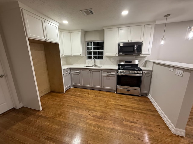 kitchen with sink, decorative light fixtures, decorative backsplash, white cabinets, and appliances with stainless steel finishes