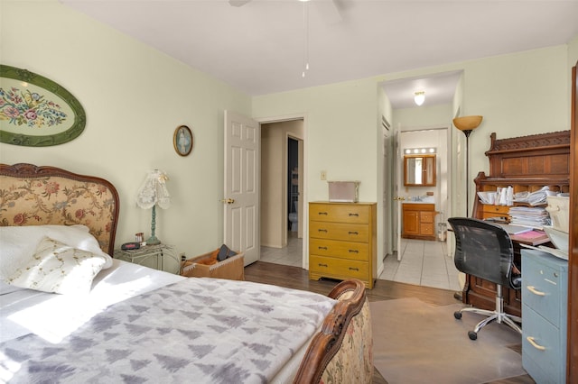 bedroom with light wood-type flooring, ensuite bath, ceiling fan, and sink