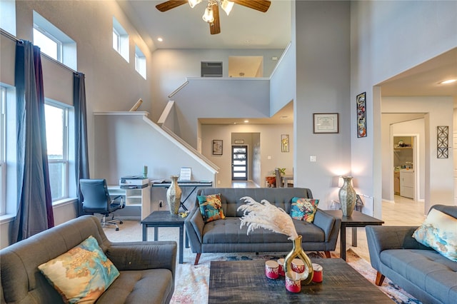 living room featuring a wealth of natural light, ceiling fan, separate washer and dryer, and a high ceiling