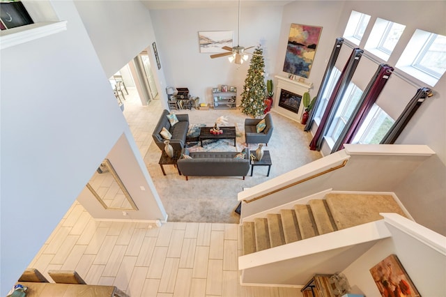 living room with a high ceiling, ceiling fan, a healthy amount of sunlight, and wood-type flooring