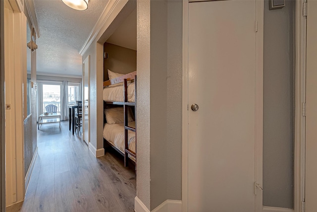 hall with ornamental molding, a textured ceiling, and light wood-type flooring