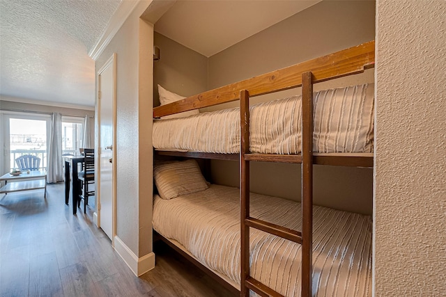 bedroom with dark wood-type flooring, a textured ceiling, and ornamental molding