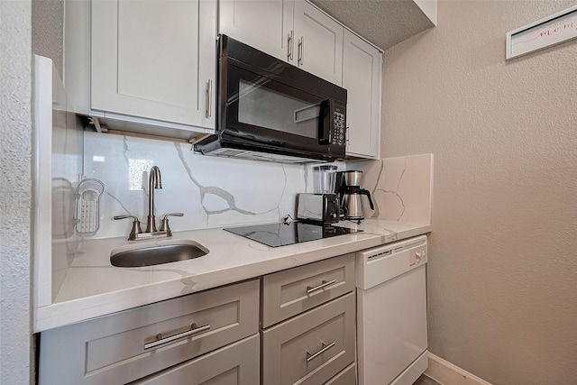 kitchen with black appliances, backsplash, light stone countertops, and sink