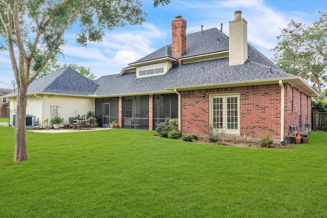 rear view of property featuring a lawn, a patio area, a sunroom, and central AC