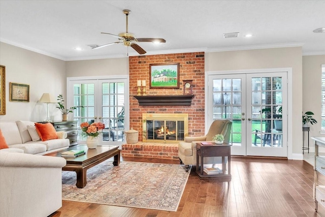 living room featuring crown molding, french doors, wood-type flooring, and a brick fireplace