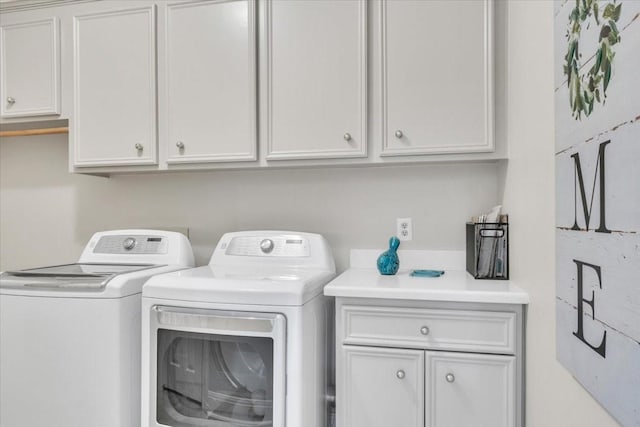 laundry room featuring washing machine and clothes dryer and cabinets