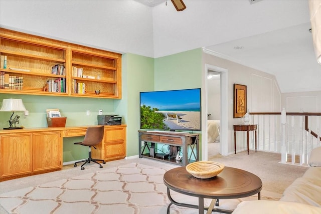 carpeted office with crown molding, ceiling fan, built in desk, and vaulted ceiling