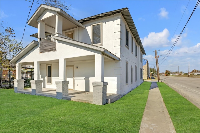 view of home's exterior with a lawn, a balcony, and a porch