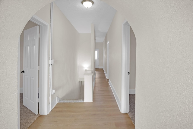 corridor featuring a textured ceiling and light hardwood / wood-style flooring