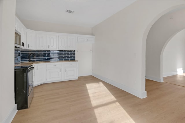 kitchen with black electric range oven, tasteful backsplash, white cabinetry, and light hardwood / wood-style flooring