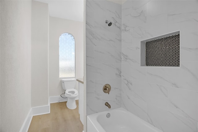 bathroom featuring a wealth of natural light, hardwood / wood-style floors, tiled shower / bath combo, and toilet