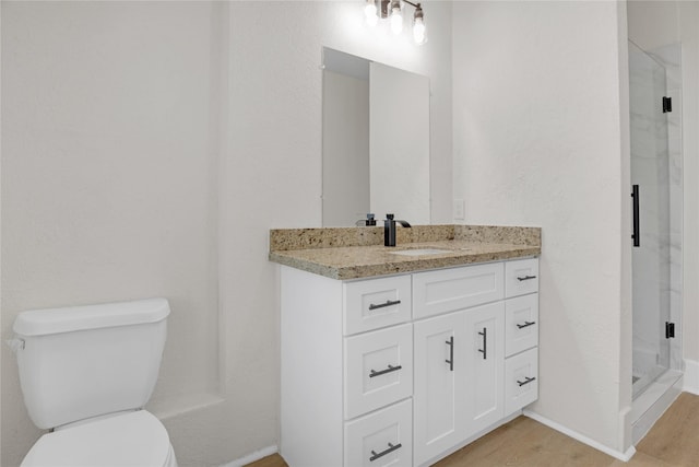 bathroom with an enclosed shower, vanity, toilet, and hardwood / wood-style floors