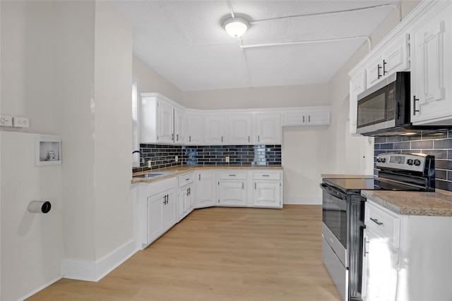 kitchen with sink, tasteful backsplash, light hardwood / wood-style floors, white cabinets, and appliances with stainless steel finishes