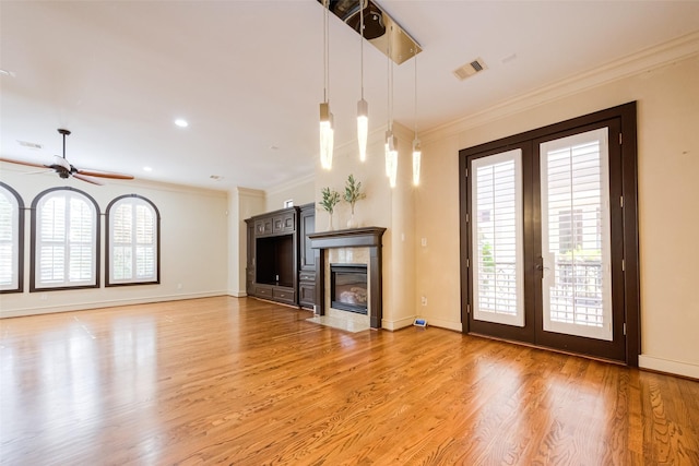 unfurnished living room featuring crown molding, ceiling fan, a healthy amount of sunlight, and wood-type flooring