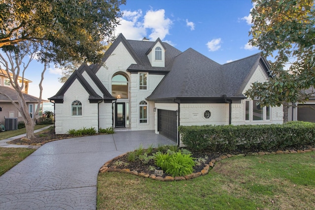 french country inspired facade with a front lawn, central AC unit, and a garage