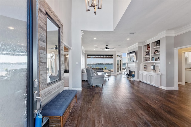 foyer entrance featuring hardwood / wood-style floors, ceiling fan with notable chandelier, and crown molding